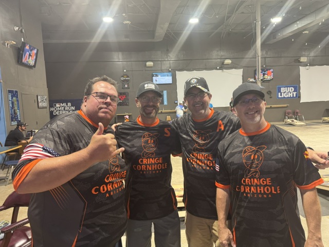 Cornhole team in matching jerseys posing with thumbs up