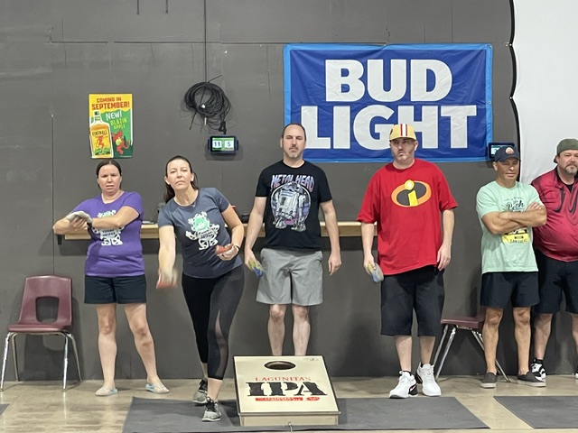Player mid-toss at a cornhole board