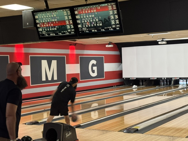 Bowler mid-approach beneath glowing tournament scoreboards