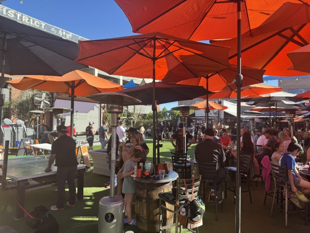 Sunny bar patio crowd under orange umbrellas